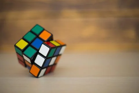 Colored 3D combination puzzle Rubik's cube three by three lies on a wooden ta Stock Photos