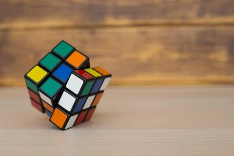 Colored 3D combination puzzle Rubik's cube three by three lies on a wooden ta Stock Photos