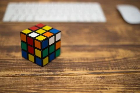 Colored 3D combination puzzle Rubik's cube three by three lies on a wooden ta Stock Photos