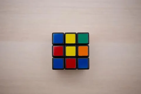 Colored 3D combination puzzle Rubik's cube three by three lies on a wooden ta Stock Photos