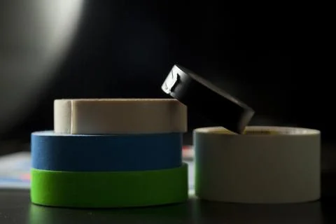 Colored adhesive tapes stacked on a table and black background. With spot lig Stock Photos
