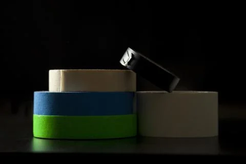 Colored adhesive tapes stacked on a table and black background. With spot lig Fotos de archivo