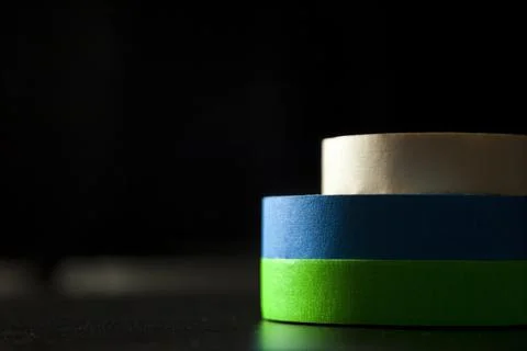 Colored adhesive tapes stacked on a table and black background. With spot lig Stock Photos