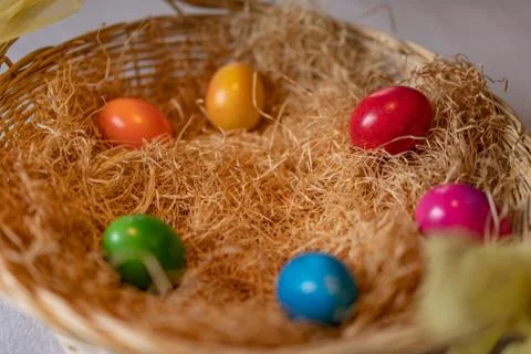 Colored and cooked easter eggs in a nest of straw in straw basket on white gr Stock-Fotos