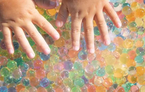 Colored balls of hydrogel touch children's hands. Sensory sensations. Stock Photos
