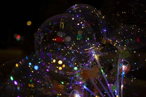 Colored balls with light bulbs inside on dark background. Texture of lights.. Stock Photos