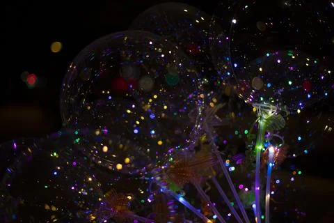 Colored balls with light bulbs inside on dark background. Texture of lights.. Stock Photos