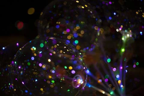 Colored balls with light bulbs inside on dark background. Texture of lights.. Stock Photos