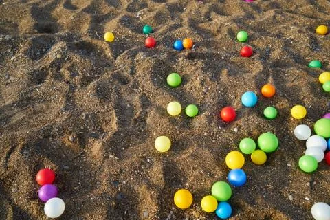 Colored balls sprinkled on the beach Stock Photos