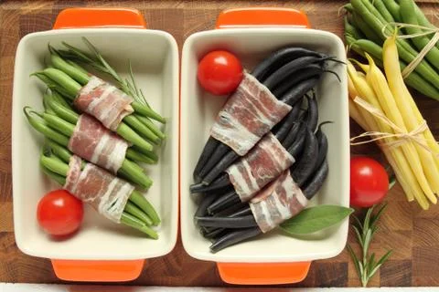Colored beans wrapped in bacon slices in casserole dish Stock Photos