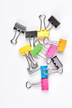 Colored binder clips on white background. Stock Photos