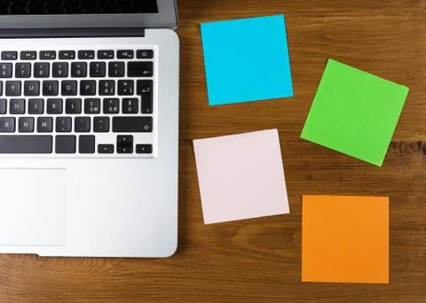 Colored blank post-it with office supplies on wooden table. Stock Photos