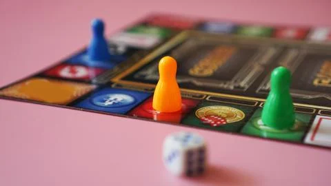Colored board game figures with dice Stock Photos