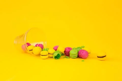 Colored, bright, sweet macaroons on a yellow background. Antigravity. Asymmetry. Stock Photos
