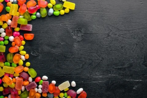 Colored candies, sweets and lollipops. On a black wooden background. Top view Stock Photos