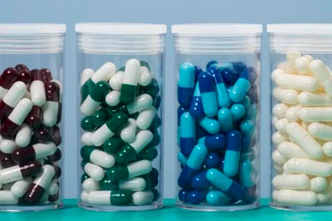 Colored capsule of medication in transparent plastic storage container Foto stock