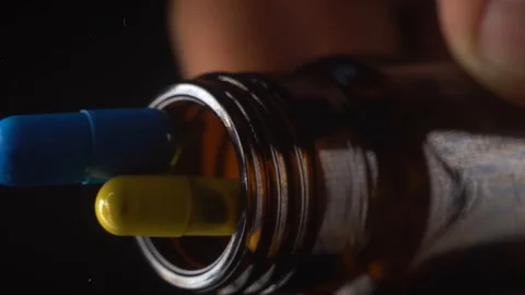 Colored capsules falling from a glass jar Stock Footage 127620175