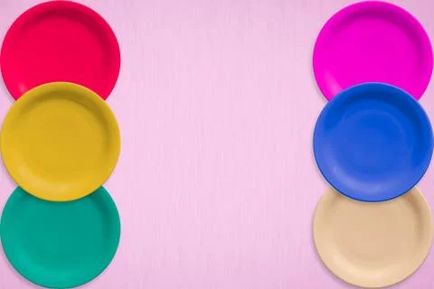 Colored ceramic round plates over on pink background Фото