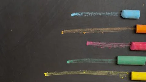 Colored chalks on black chalkboard background Stock Photos