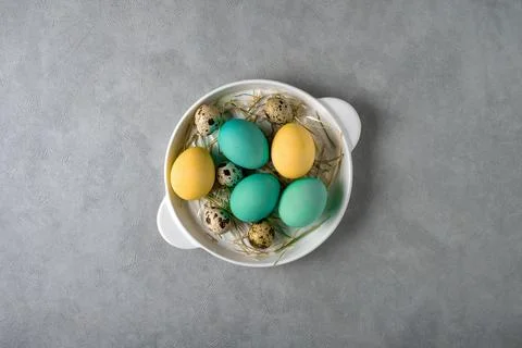 Colored chicken eggs and quail eggs in a white dish Stock Photos