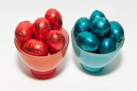Colored chocolate easter eggs in glass cups of the same color Stock Photos