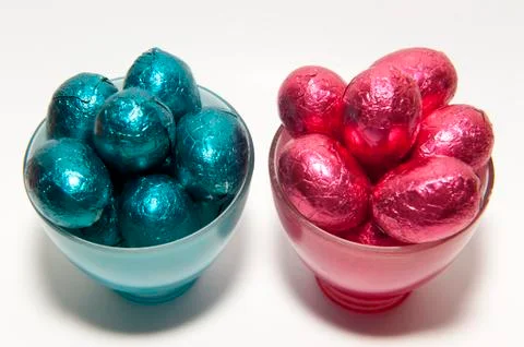 Colored chocolate easter eggs in glass cups of the same color Stock Photos