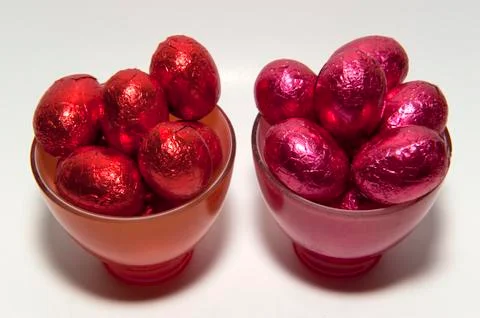 Colored chocolate easter eggs in glass cups of the same color Stock Photos