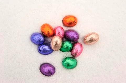Colored chocolate easter eggs in a snowy white background Stock Photos