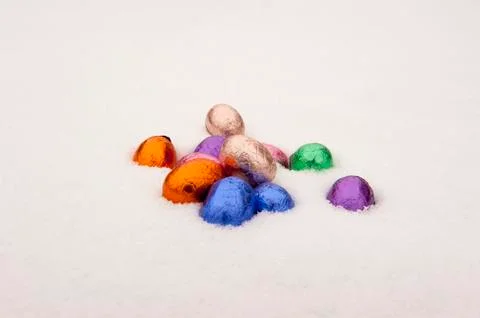 Colored chocolate easter eggs in a snowy white background Stock Photos