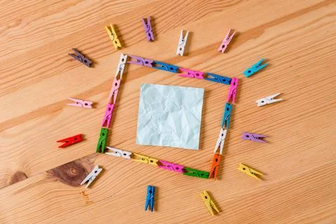 Colored clothespin placed in a square shape and pointing to a empty rectangle Stock Photos