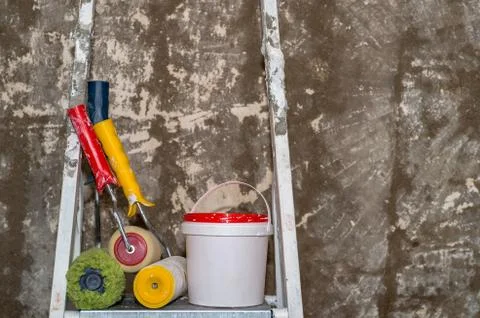 Colored construction rollers with a bucket stand on a stepladder on the Stock Photos