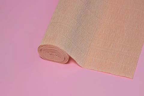 Colored corrugated paper. Roll of beige corrugated paper on a pink background. Stock Photos