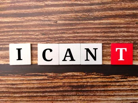 Colored cube with text I CAN T on a wooden background. Stock Photos