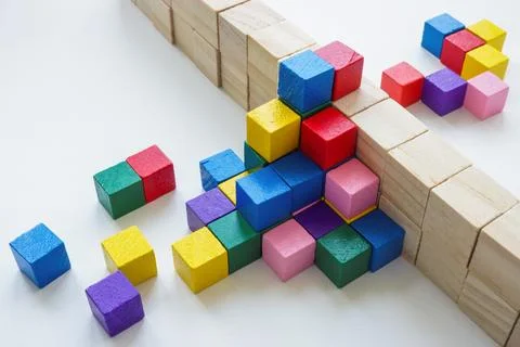 Colored cubes overcome an obstacle in the form of a wall. Creativity or Stock Photos