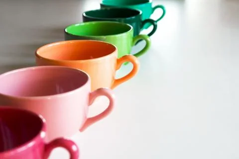 Colored cups on the table background Stock Photos