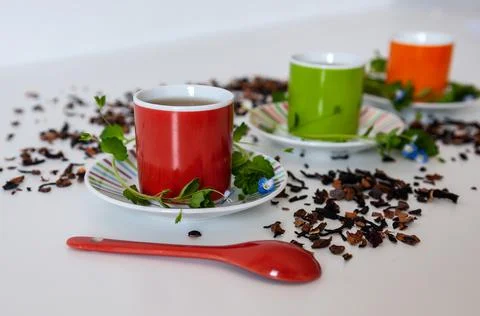 Colored cups of tea on a white table Stock Photos