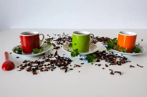 Colored cups of tea on a white table Stock Photos