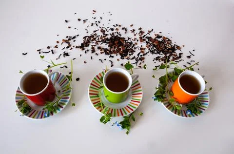 Colored cups of tea on a white table Stock Photos