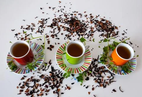 Colored cups of tea on a white table Stock Photos