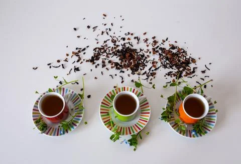 Colored cups of tea on a white table Stock Photos