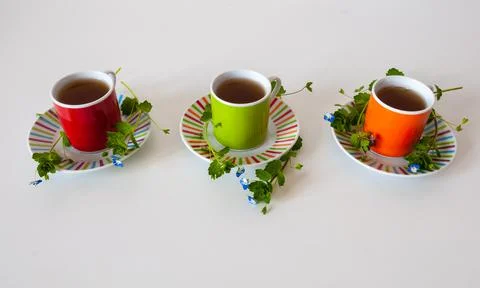 Colored cups of tea on a white table Stock Photos