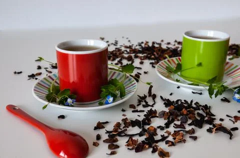 Colored cups of tea on a white table Stock Photos