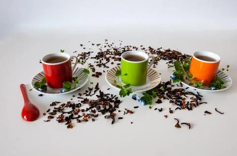 Colored cups of tea on a white table Stock Photos