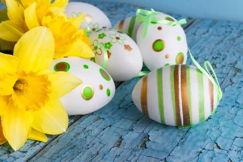 Colored decorative Easter eggs and a bouquet of yellow narcissus 库存照片