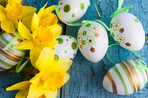 Colored decorative Easter eggs and a bouquet of yellow narcissus Stock Photos