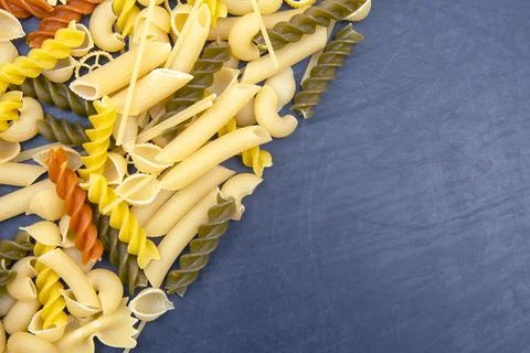 Colored different types of Italian pasta on a dark background. food texture.  Stock Photos