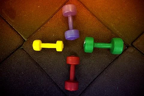 Colored dumbbells on a black background Stock Photos