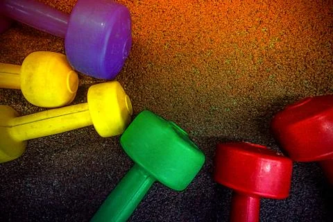 Colored dumbbells on a black background Stock Photos