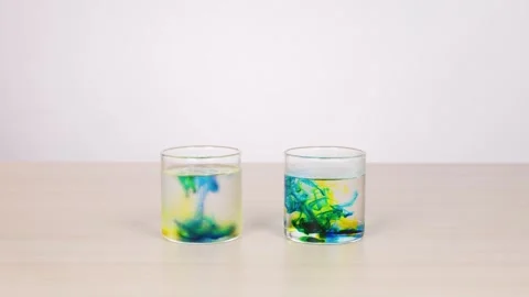 Colored Dye Diffusing in Two Glasses of Water on Table Stock Footage 319002945