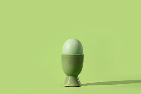 Colored easter egg in green egg cup, on green Stock Photos